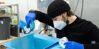 Projektityöntekijä ja LABin opiskelija Eetu Mäntynen syöttää jätemuovia murskaukseen.