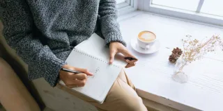 Henkilö kirjoittaa muistiinpanoja