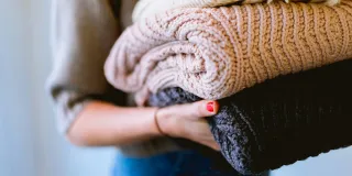 Henkilö pitelee neulekasaa sylissään.