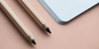 Notebook and pencil on a beige background.