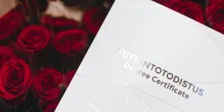 Tutkintotodistuskansio ja ruusut.