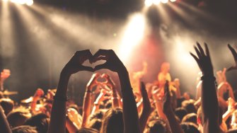 Kuvassa katsoja tekee käsillään sydämen nauttiessaan konsertista