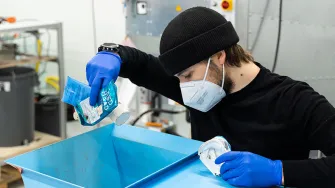 Projektityöntekijä ja LABin opiskelija Eetu Mäntynen syöttää jätemuovia murskaukseen.