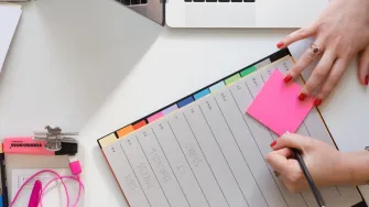 Projektityön arkea kuvaavat muistilaput, korostustussi, kansion välilehdet