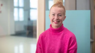 Kuvassa YAMK-opiskelija Jenni Hämäläinen istuu kampuksen käytävälle avautuvan ikkunan edessä.