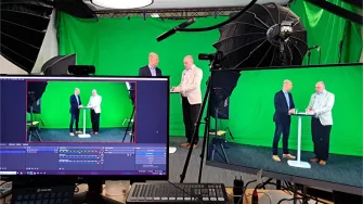 Vihreän taustakankaan edessä kaksi miestä keskustelemassa studiossa 