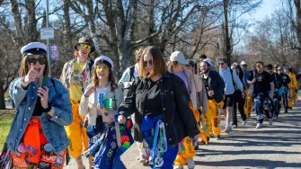 Kuvassa opiskelijoiden muodostama vappukulkue. Opiskelijoilla eri värisiä haalareita, etualan tyttö näyttää peukkua. 