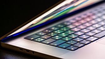 A laptop computer with a half-open screen on a dark background.