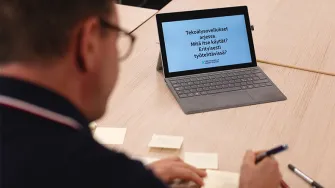 Mies kirjoittaa tekoälytyöpajassa post-it -lappuja pöydällä