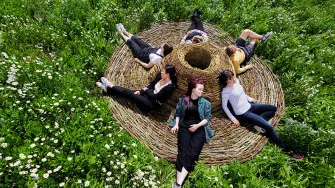 Naisia niityllä makoilemassa