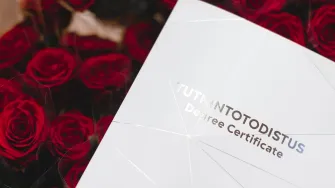 Tutkintotodistuskansio ja ruusut.