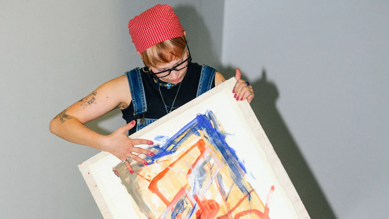 Kuvataiteilija pitää käsissään maalausta