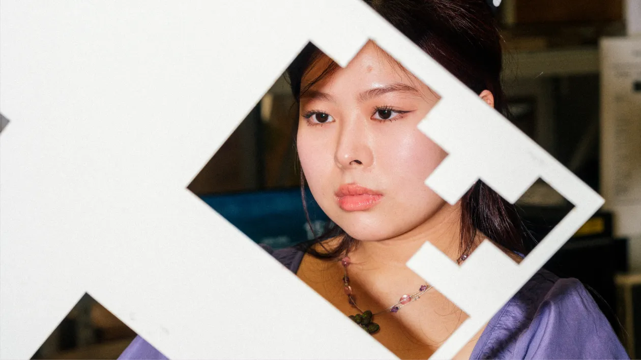 Nainen katsoo läpi kuvakehyksen takaa