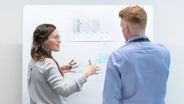 Ihmiset valkotaulun edessä keskustelemassa