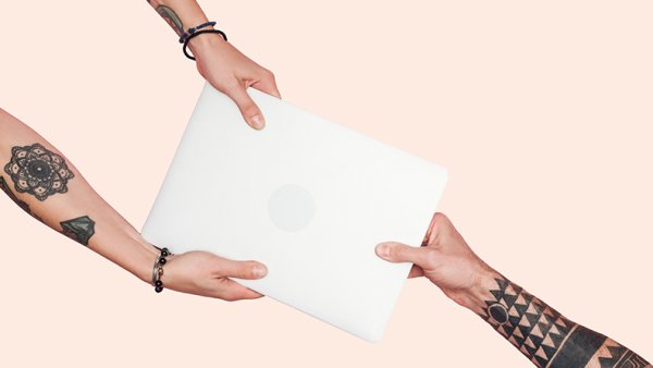 Tattooed people pulling laptop on a light beige background.