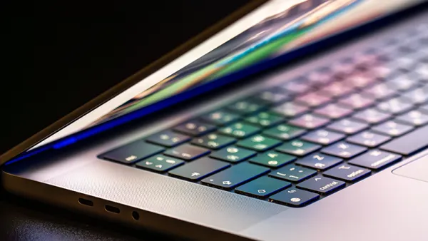 A laptop computer with a half-open screen on a dark background.