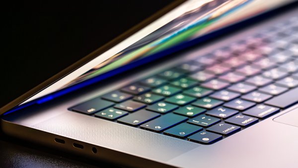 A laptop computer with a half-open screen on a dark background.