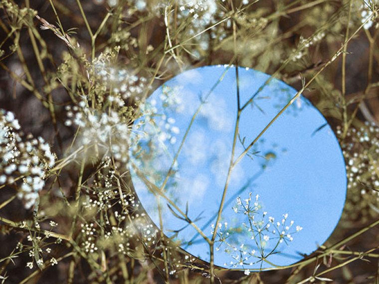 Sky landscape in a round mirror lying on the grass