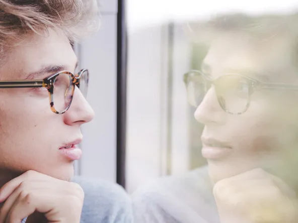 A man with glasses and his reflection in window