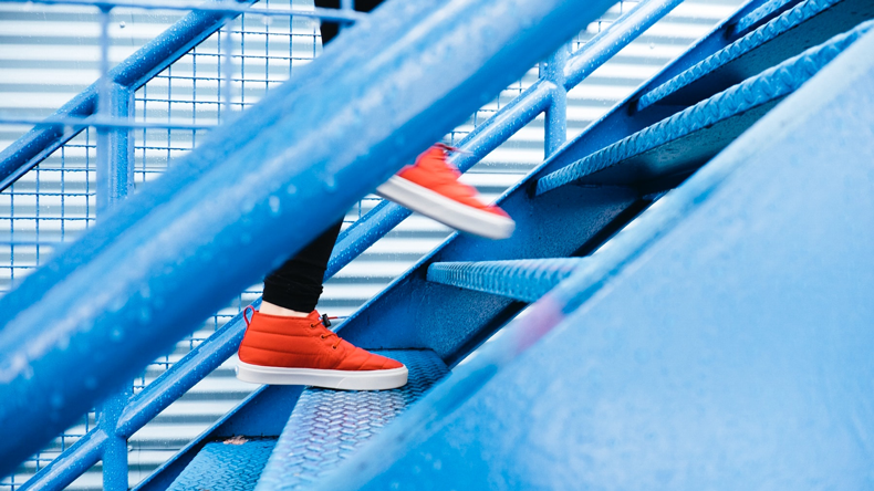 Feet with orange sneakers climbs stairs