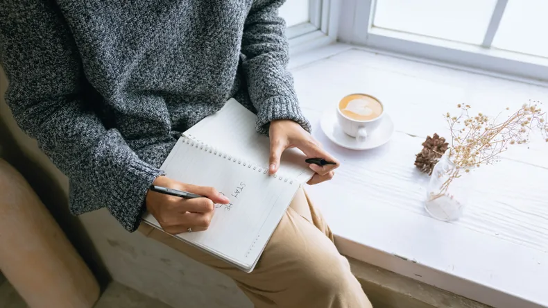 Henkilö kirjoittaa muistiinpanoja