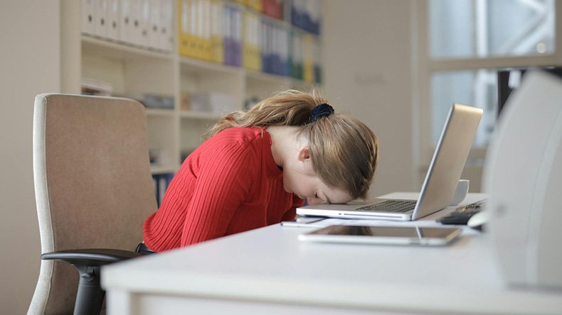 Nainen painaa päätään työpöytää vasten turhautuneena
