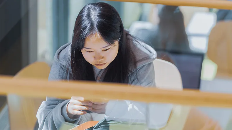 Kuvassa LABin opiskelija istuu ja katsoo puhelinta.