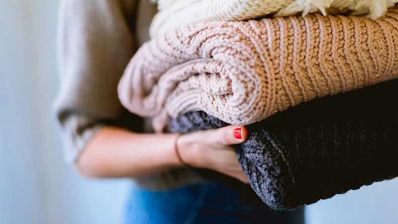 Henkilö pitelee neulekasaa sylissään.