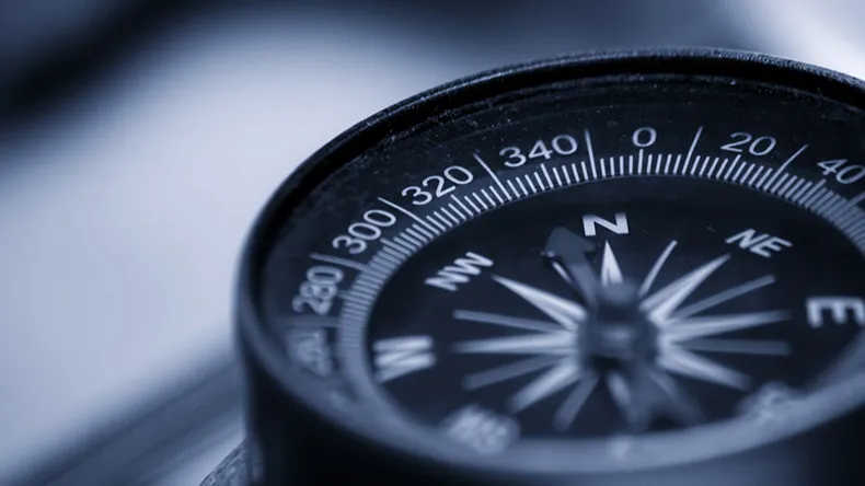 Sini-harmaasävyinen kompassi pöydällä