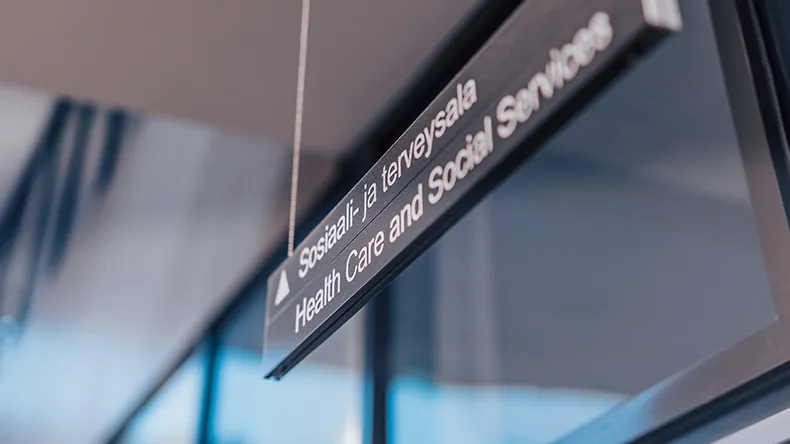 Sosiaali- ja terveysalan kyltti roikkuu katosta.