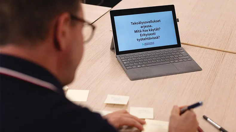 Mies kirjoittaa tekoälytyöpajassa post-it -lappuja pöydällä