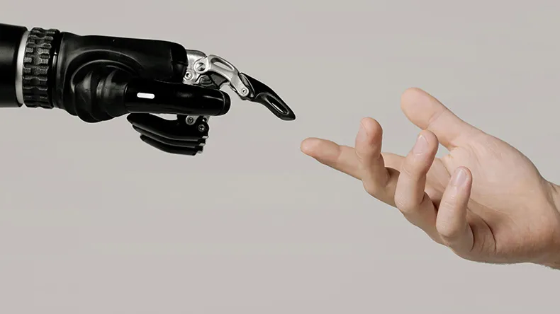 Robottikäsi ja ihmiskäsi kurottautuvat toisiaan kohden