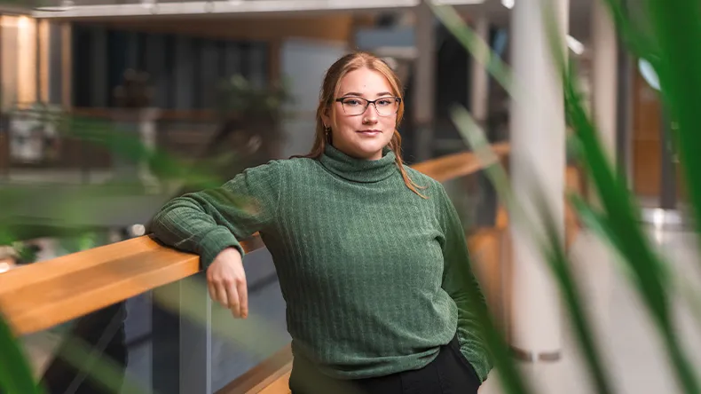 LAB-ammattikorkeakoulun opiskelija Essi Jäkälä nojaa kampuksella kaiteeseen ja katsoo kameraan.